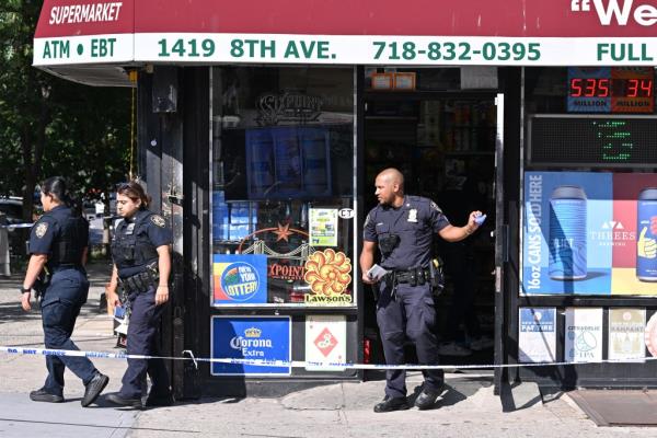 Two police officers standing outside a deli in South Slope, Brooklyn where a man was shot during a botched robbery